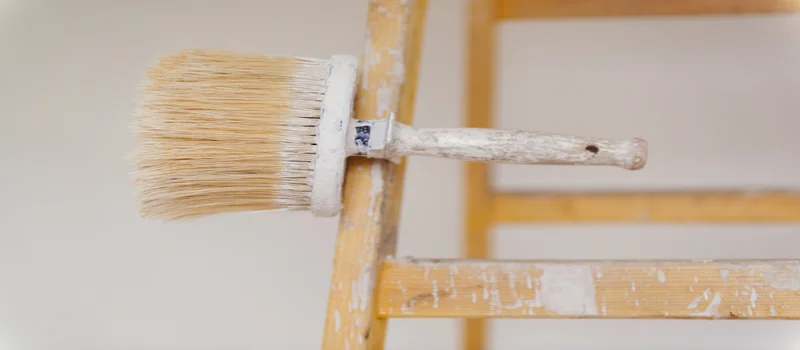 Pinceau posé sur le bord d'une échelle en bois