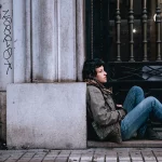 Jeune femme assise par terre dans la rue contre un mur