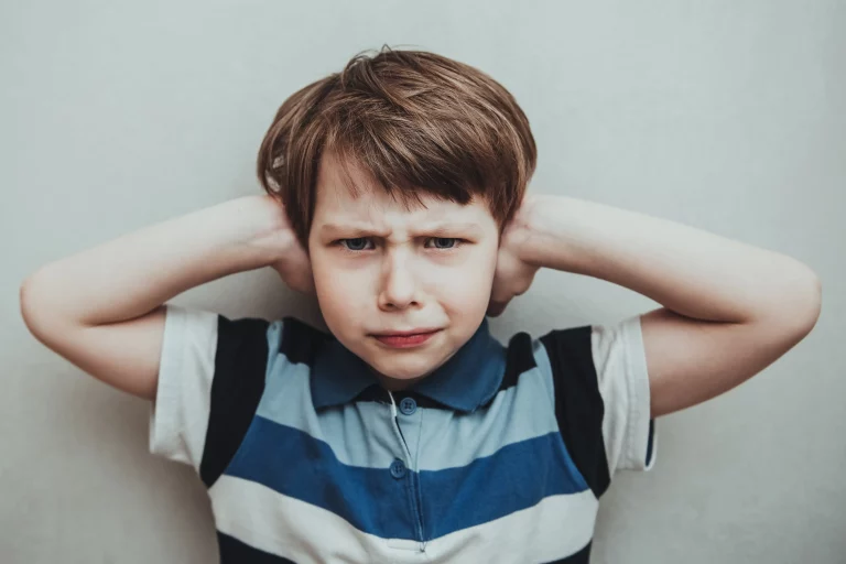 Jeune garçon qui se bouche les oreilles pour ne plus entendre les cris